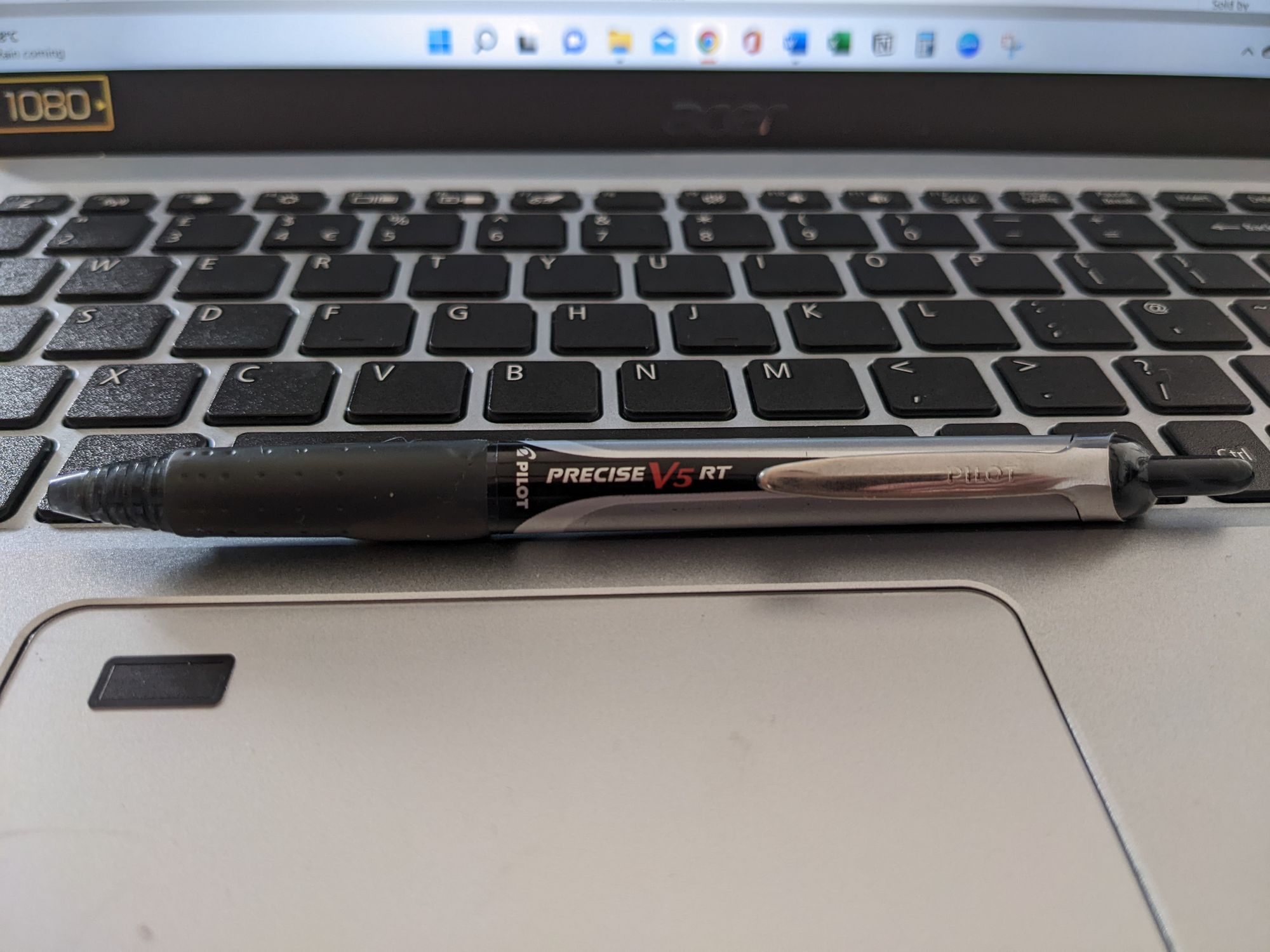 A Pilot V5 RT black rollerball pen on a laptop keyboard