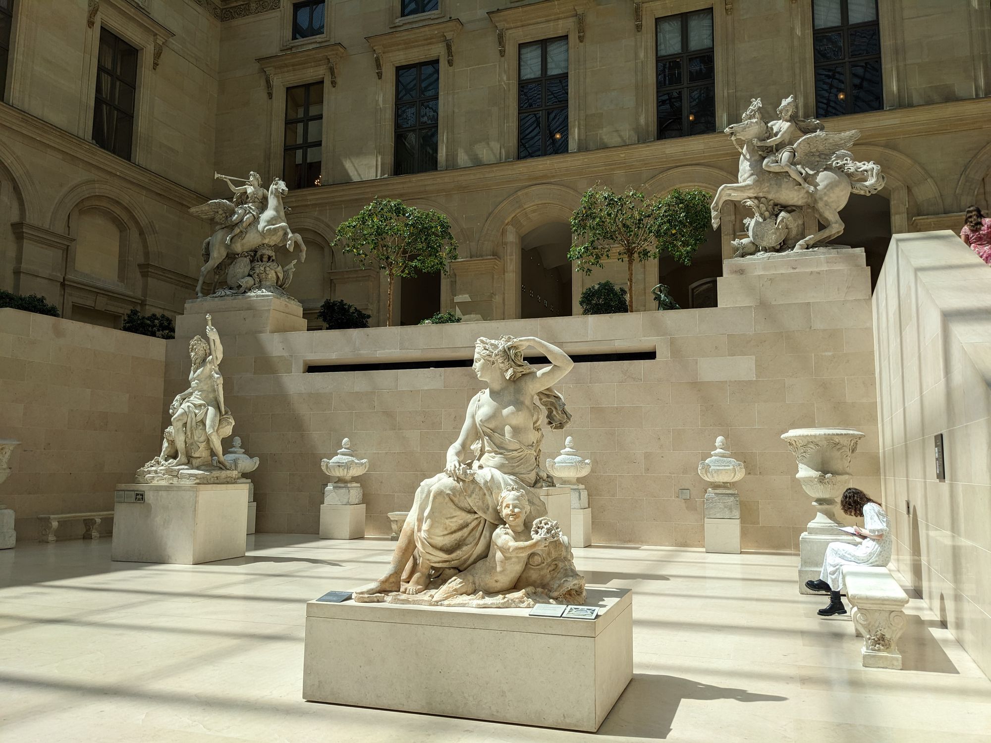 Statues inside the Louvre lit by summer sunshine