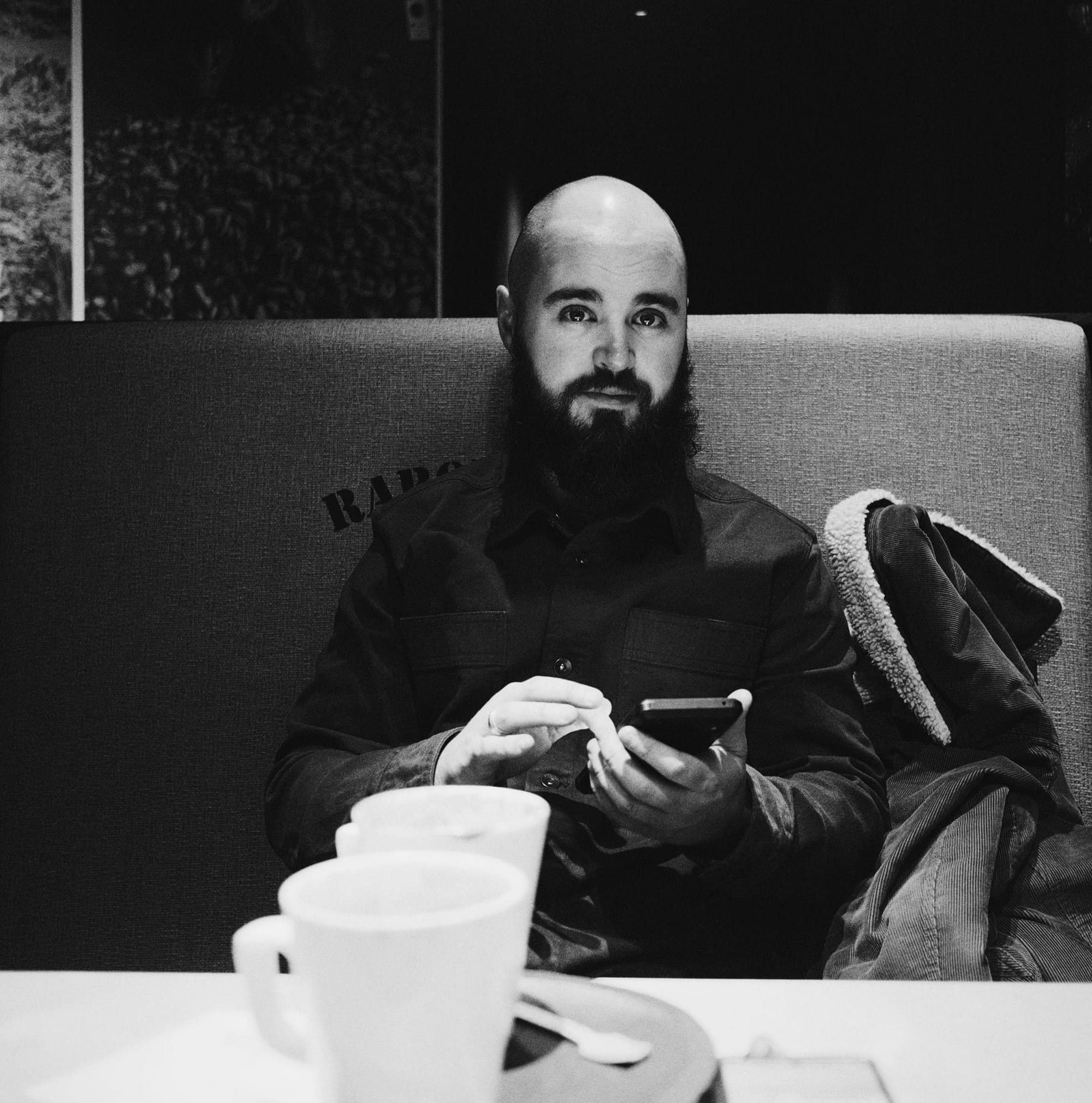 Bald man with big beard Ben Craske in a cafe with a hot chocolate