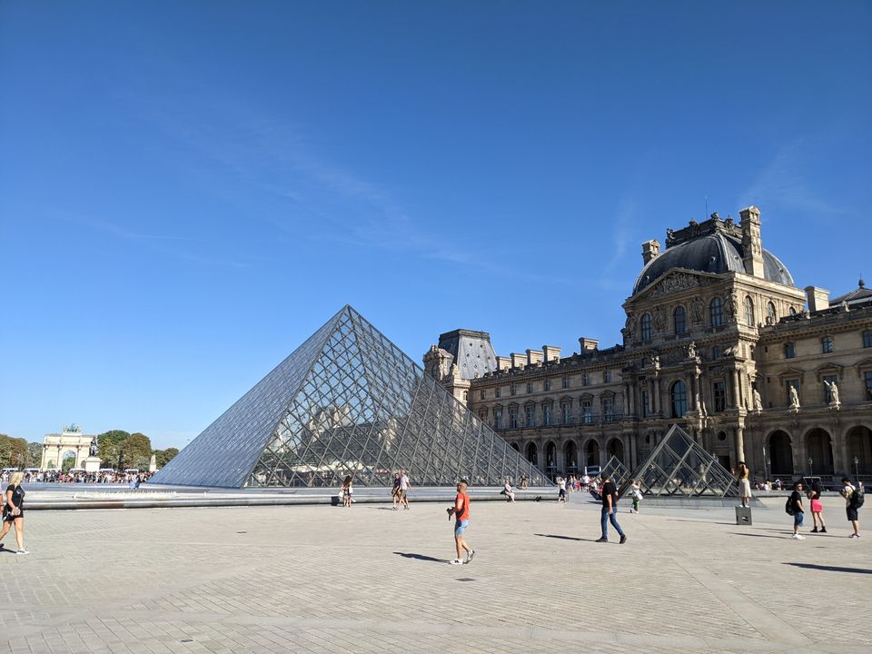 The Louvre Museum pyramid entrance on a sunny day in Paris in July 2022.
